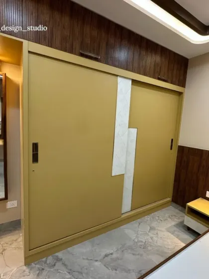 This image shows the custom sliding wardrobe, where the mustard yellow finish is paired with a textured white accent and a dark wood frame. The full-length mirror on the side is a practical addition that also helps to make the space feel larger.