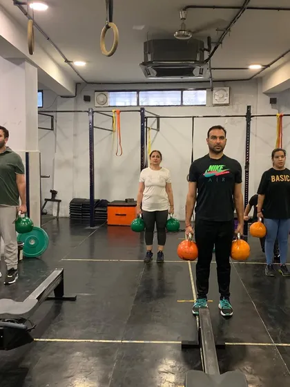 Members performing a farmer's hold with kettlebells. This simple but effective exercise is fantastic for building grip strength, core stability, and shoulder endurance.