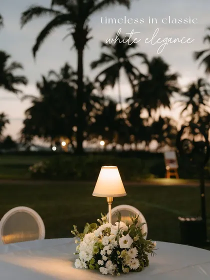 A table centerpiece with a lamp, set against the beautiful Goan sunset. The decor is designed to be timeless and elegant.