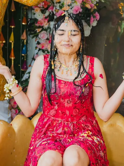 A bride enjoying her Haldi ceremony, being showered with water and blessings, a moment of refreshing joy.