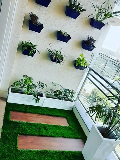 This balcony design combines floor planters with a nine-pot vertical garden on the wall, maximizing the green space.