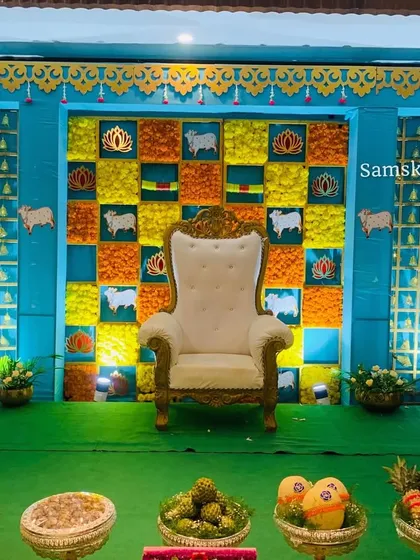 A unique baby shower backdrop with a turquoise frame and a checkerboard pattern of flowers and traditional motifs. The design combines bright colors and cultural symbols for a memorable event.