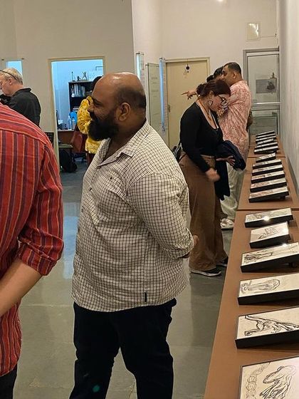 Visitors studying the long table of reverse paintings.