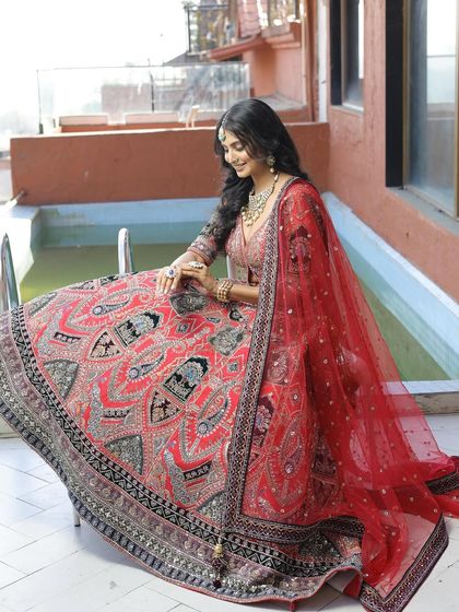 This red lehenga features unique black and silver threadwork, offering a contemporary twist on a traditional design. It's perfect for the bride looking for something different.