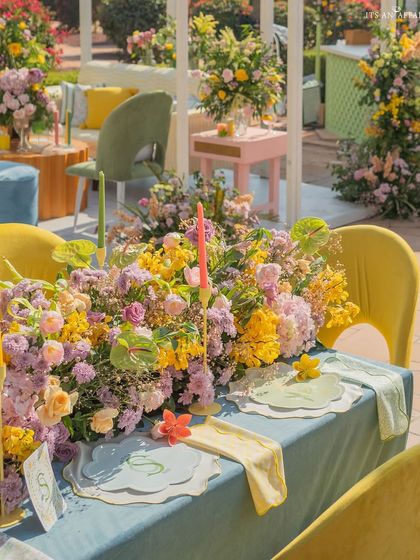 A colorful tablescape at the 'Spring Garden Brunch', with a mix of yellow, pink, and purple flowers and pastel-colored candles.