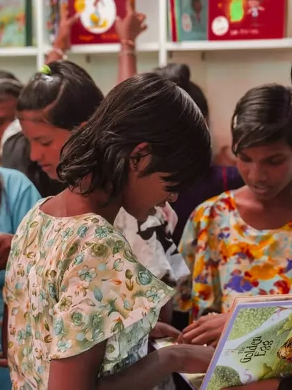 A group of girls eagerly browse the new book collection. Their excitement reflects the magic and hope that this new library represents.