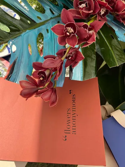 A close-up of an orchid and a menu from the Farm Rio event, showcasing the beautiful, tropical floral arrangements that were central to the tablescape design.
