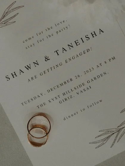 A flat-lay of the elegant wedding invitation with the couple's rings, a beautiful way to capture the details of the event.