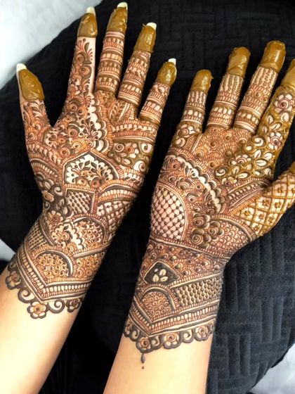 A classic bangle-length mehendi design. The pattern stops at the wrist, creating the look of an intricate cuff, with detailed work covering the entire palm and fingers.