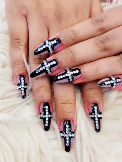 A full view of the rhinestone cross design on black stiletto extensions, showcasing a daring and edgy aesthetic.