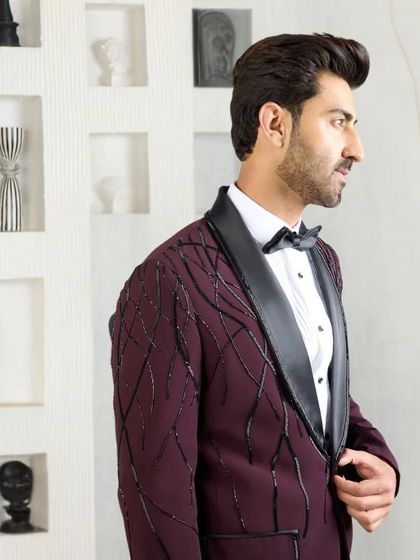 A side profile of the wine-colored tuxedo, showing how the sleek silk lapel and tailored fit create a flattering and elegant line.
