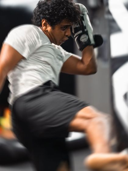 The blur of a fast roundhouse kick hitting the heavy bag captures the explosive power we teach.
