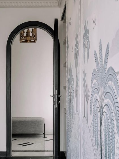 A detail of the home office lounge, with an arched doorway and tropical wallpaper panels. The design is full of quiet, eclectic details.