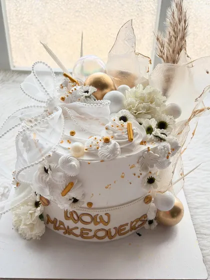 I designed this cake for a studio relaunch, focusing on a modern and luxurious feel. It's all about the details: the clean white finish, gold accents, delicate ribbons, and a mix of textures.