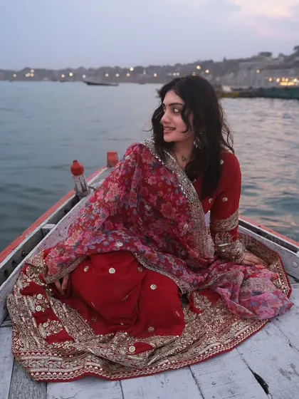 Red drapes, Ganga waves, and Banaras in her soul. A beautiful portrait capturing a woman's serene expression as she floats on a boat at dusk.