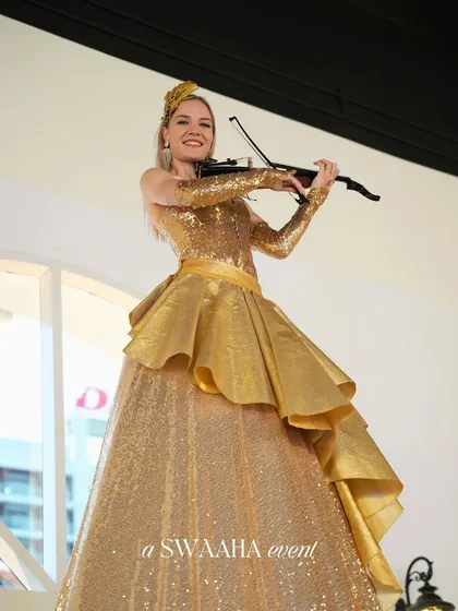 A violinist in a golden ballgown, another example of the high-class, themed musical performers I arrange.