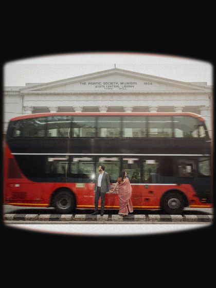 The iconic red double-decker bus adds a classic Bombay touch. This shot, with the historic Asiatic Society library in the background, is a perfect blend of nostalgia and modern love.