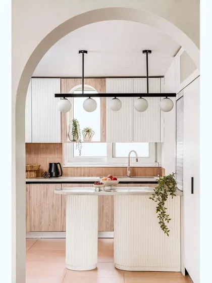 An archway frames the view into the clean, uncluttered kitchen, where all appliances are concealed to maintain a minimalist aesthetic.