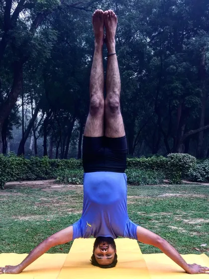 This is Mukta Hasta Sirsasana (Tripod Headstand) with arms extended wide. This variation removes the stable base of the forearms, demanding significantly more core engagement and shoulder stability.