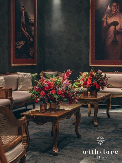 Two elegant coffee tables, each with a stunning red floral centerpiece. The seating is arranged to create multiple small, intimate zones within the larger event space.