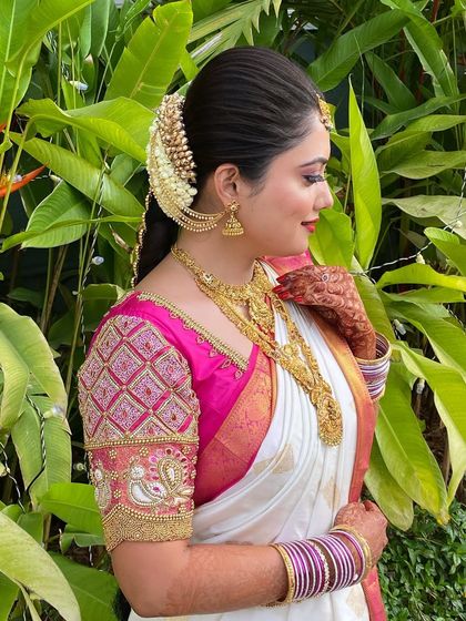 A side profile of the bride, showcasing how the traditional hairstyle with jasmine and temple jewellery beautifully frames her face. This is a classic and elegant choice for any South Indian bride.