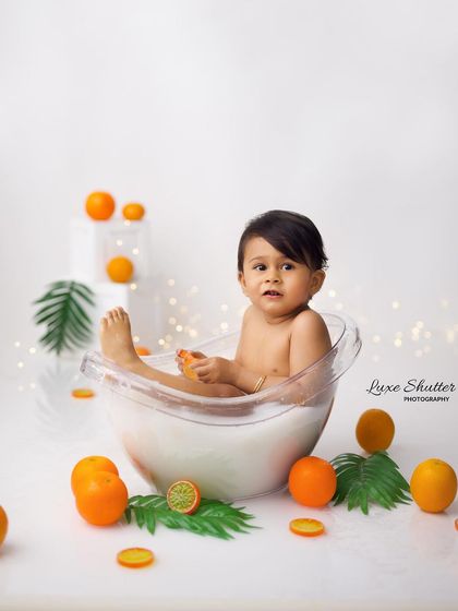 A curious look from a baby in our minimalist fruit bath setup. The clean white background makes the orange props pop.