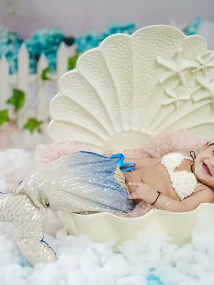A dreamy mermaid photoshoot for a six-month milestone. This little mermaid is all smiles, relaxing in a giant seashell prop surrounded by a sea of soft, fluffy clouds. It's a whimsical theme perfect for celebrating your baby's half-birthday.