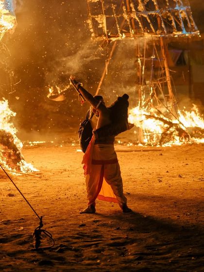 A priest performs a ritual in front of the burning effigies, a moment of tradition amidst the spectacle.