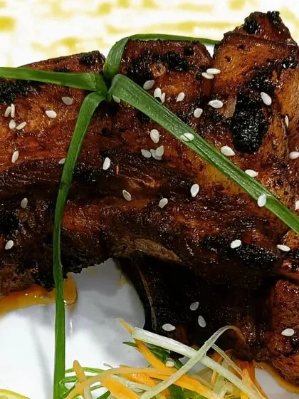 A close look at my smoked and glazed pork ribs. Each piece is cooked to be tender with a charred, flavorful exterior, then garnished with sesame.