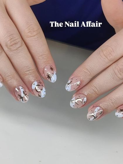 A celestial-themed manicure with gold foil moons and stars over a milky white tip. The negative space design keeps it feeling modern and chic.