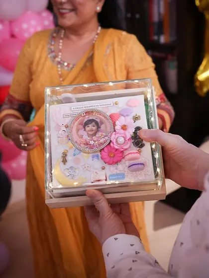 The moment of gifting. The personalized baby album, enclosed in its lit-up acrylic box, is presented to the family.