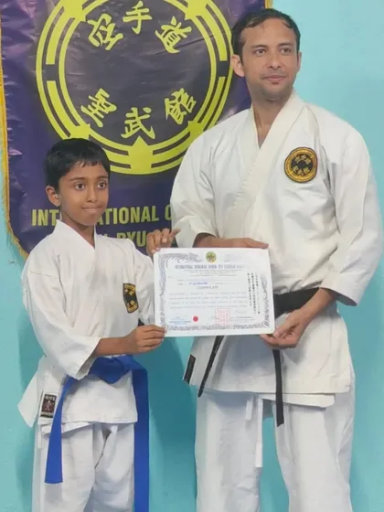 A young student proudly receives his 6th Kyu (blue belt). His focus during training is an example to others in the dojo.