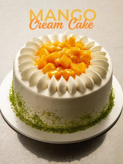 A celebration of seasonal flavour, this is my Mango Cream Cake. It's topped with a generous amount of fresh, diced mango and surrounded by delicate swirls of light cream, with a sprinkle of green pistachio dust at the base.