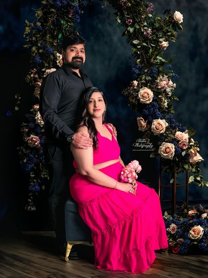 A classic studio portrait with a romantic twist. The couple is framed by a beautiful floral arch, creating a timeless image with a touch of modern elegance.