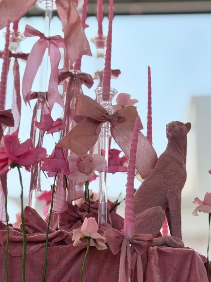 A detailed shot of one of our sculptural centerpieces. A flocked pink panther sits among tall candles, silk ribbons, and delicate flowers, showcasing our use of unique, artistic elements to enhance a theme.