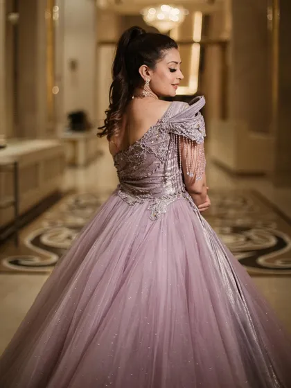 The back view of our royal lavender ball gown, showcasing the asymmetrical design and the beautiful way the silver embroidery wraps around the bodice.