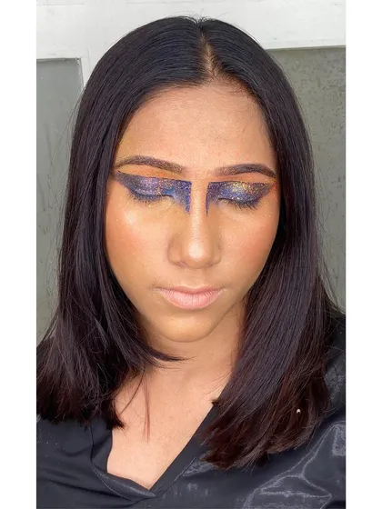 A view with eyes closed to showcase the full glitter application and the unique shape of this editorial eye makeup. This highlights the precision required for such graphic looks.