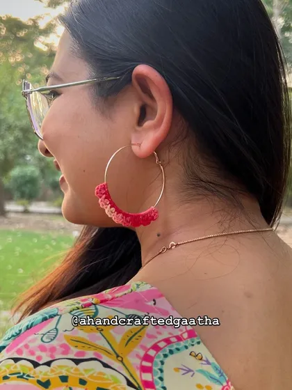 A side profile view of the crimson 'Naazakat' hoops being worn. You can see how beautifully they frame the face while being delicate and light.