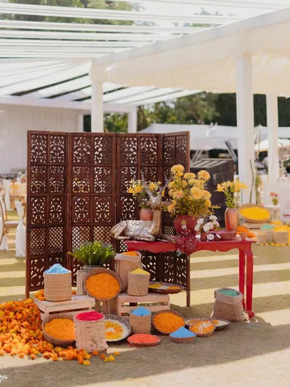A station piled high with organic colors and marigold petals for the 'Haldi Holi' party. We love creating interactive elements that get guests involved in the fun.