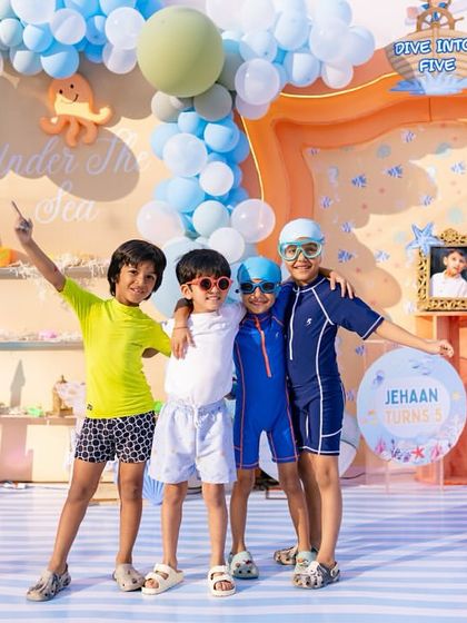 The birthday boy and his friends, ready for the pool in their swim gear, posing in front of the beautiful backdrop. These are the moments they'll remember.