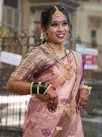 This bride looks absolutely radiant in her peach and violet Kanjivaram saree. We pre-pleated it with tiny, sharp folds to match the grandeur of her traditional South Indian bridal look.