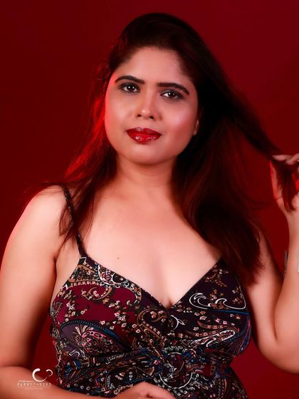 A classic fashion pose that is both elegant and alluring. The red background adds a touch of drama.