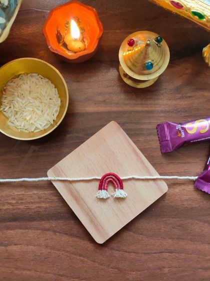 A cute and simple handmade rakhi featuring a small embroidered rainbow. This is a unique design perfect for celebrating the bond of siblings.
