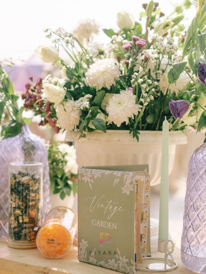 When the details have no chill. A vintage garden-themed book, custom chocolates, and beautiful florals create a setup that's giving luxury with a wink.