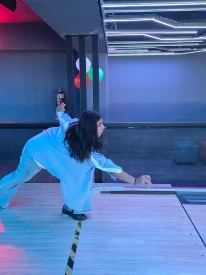 A player gets low to the ground for a precise roll, showing that bowling can be a game of skill and technique.