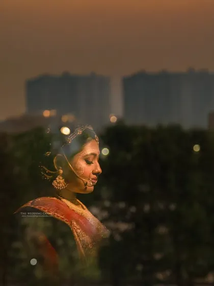 An unconventional bridal portrait, placing the bride against a modern city skyline at dusk. This creative shot blends tradition with a contemporary urban environment, telling a unique story.