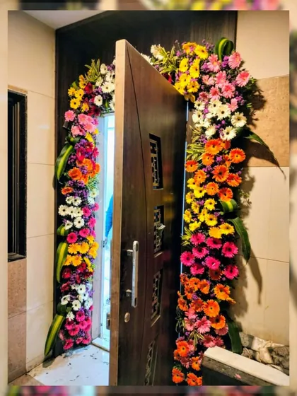 A burst of color to welcome guests. This door arch is crafted with a vibrant mix of gerbera daisies in shades of orange, pink, yellow, and white, making for a cheerful and lively entrance.