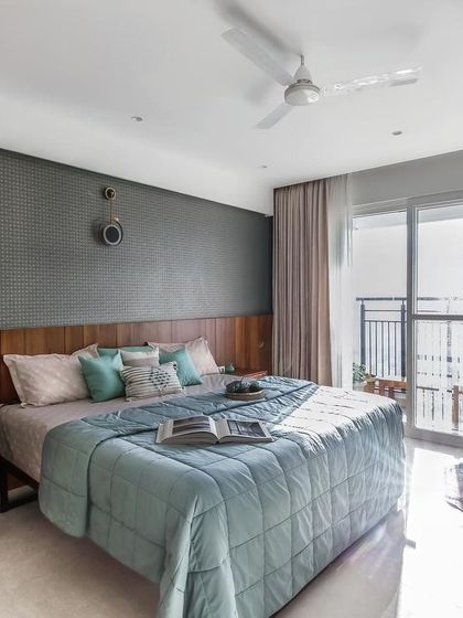The master bedroom in the apartment project, designed as a tranquil retreat. A textured wallpaper accent wall is paired with a wooden headboard and soft, layered textiles in calming shades of blue and beige.