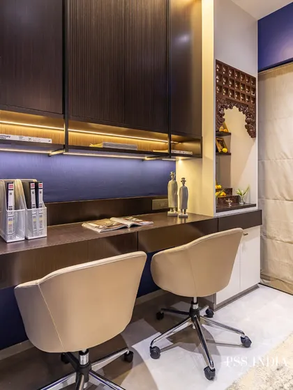 This image showcases a shared home office that also incorporates a small, beautifully carved Mandir (prayer nook), blending work and spirituality in one harmonious space.