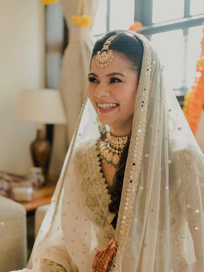 Another beautiful bride glowing in a white and gold outfit. The makeup is soft and timeless, with a focus on enhancing her natural features.